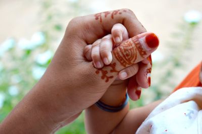 Cropped image of baby holding hand of mother