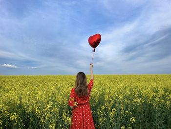 Rear view of woman standing on field against sky