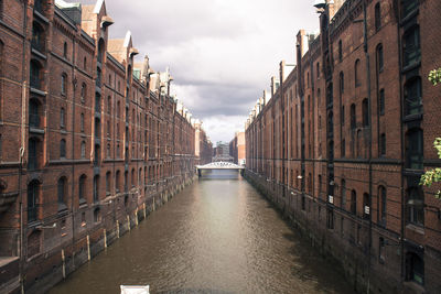 Canal amidst buildings against sky in city