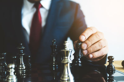 Midsection of businessman playing chess against white background
