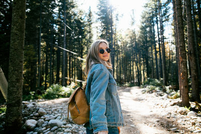 Side view of woman wearing sunglasses in forest