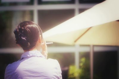 Rear view of woman smoking cigarette on sunny day