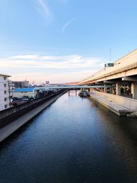 Bridge over river in city against sky