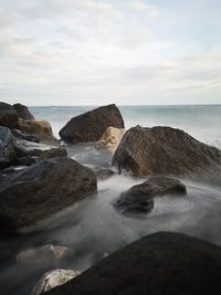 Scenic view of rocks in sea against sky