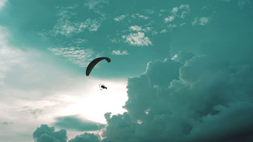 Low angle view of person paragliding against sky