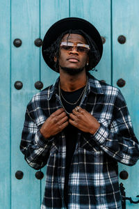 Young man wearing sunglasses standing against wall