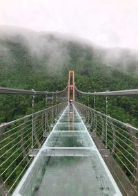 Footbridge amidst trees against sky