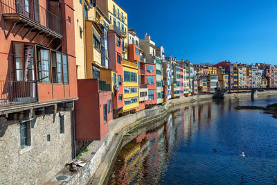 Buildings by canal against sky in city