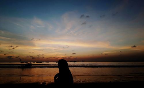 Silhouette man on beach against sky during sunset