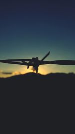 Close-up of silhouette airplane flying against clear blue sky