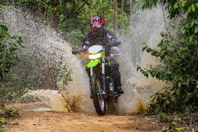 Woman riding her dirt-bike on forest track in pak chong / thailand