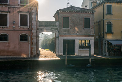 Buildings by canal against sky in city