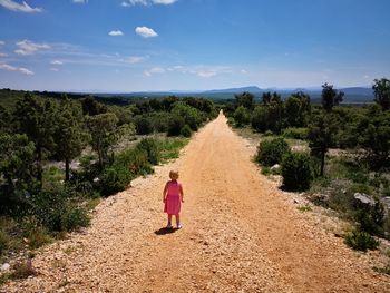 Rear view of woman walking on dirt road