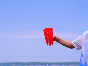 Person holding umbrella against clear blue sky