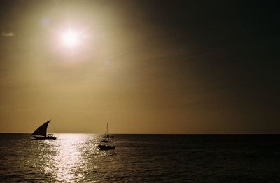 Silhouette sailboat sailing on sea against clear sky during sunset