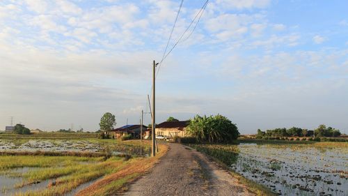 Road amidst field against sky