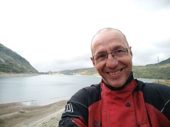 Portrait of smiling mature man standing against lake