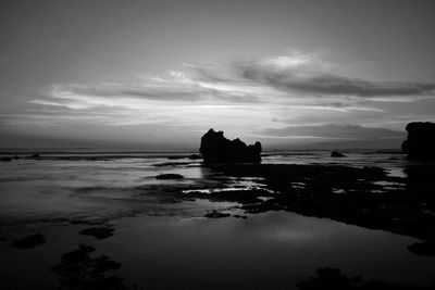 Silhouette rocks in sea against sky