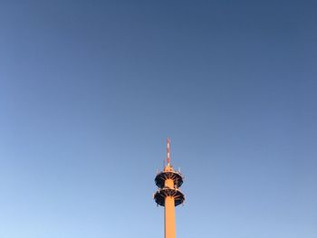 Low angle view of communications tower against blue sky