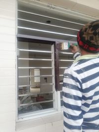 Rear view of man standing by window at home