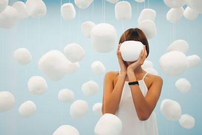Woman holding marshmallow decoration hanging against blue background