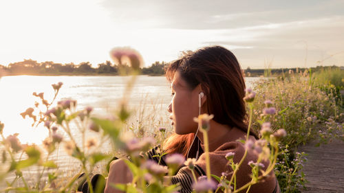 Portrait of woman on flowering plants against sky