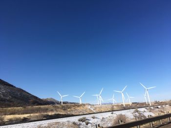 Wind turbines on field against clear blue sky