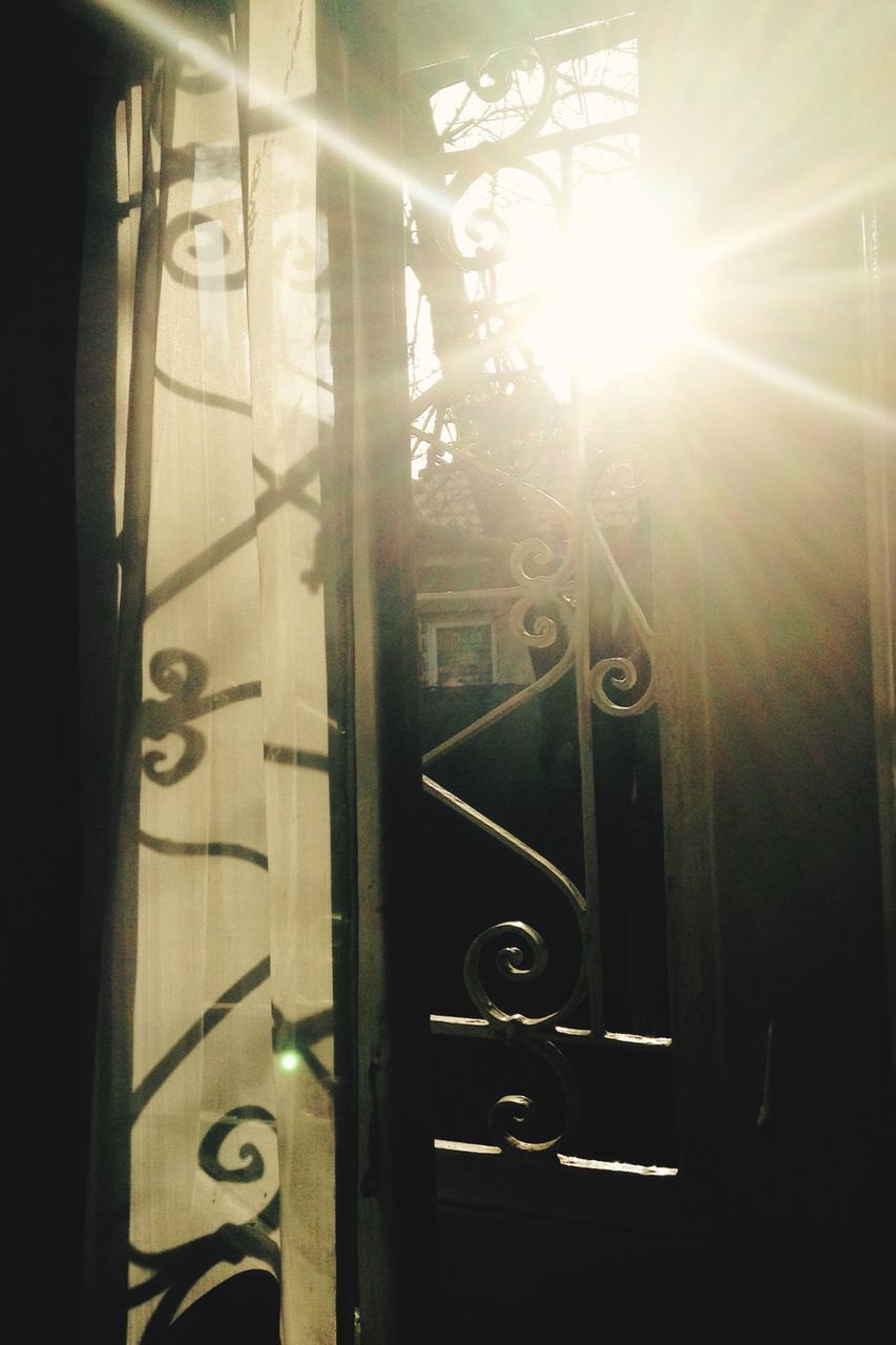 sunlight, window, sunbeam, indoors, built structure, sun, architecture, lens flare, door, protection, metal, safety, closed, no people, glass - material, day, building exterior, close-up, house, security