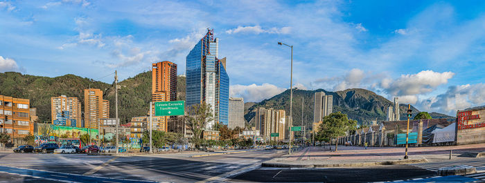 Panoramic view of street by buildings in city against sky