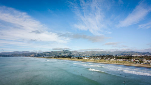 Ocean, beach, surfers and blue sky. aerial shot from new brighton beach in christchurch, new zealand