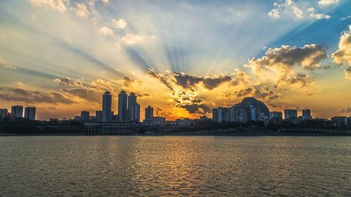 Scenic view of sea by buildings against sky during sunset