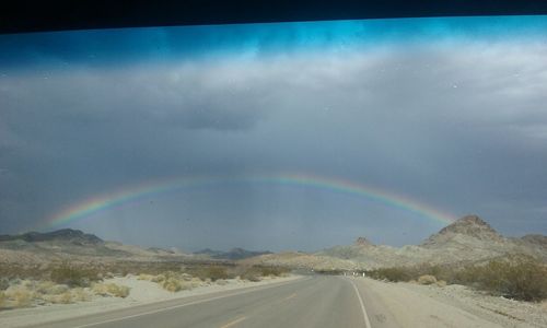 Road by mountains against sky