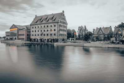 Buildings by river against sky