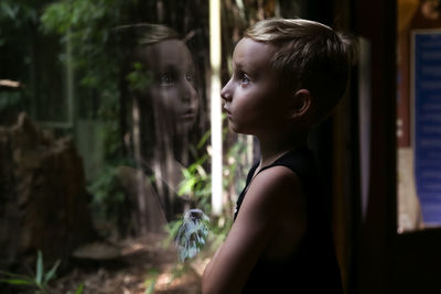 Boy looking at his reflection in glass