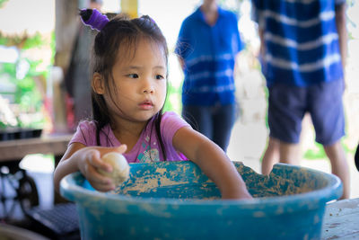 Cute girl playing with mud in container