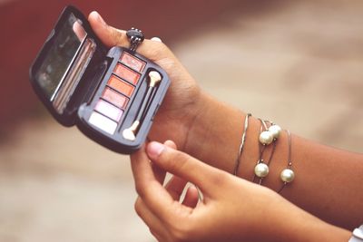 Cropped hands of woman holding make-up box