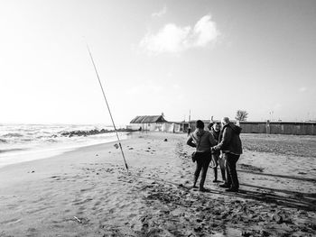 Rear view of people on beach against clear sky