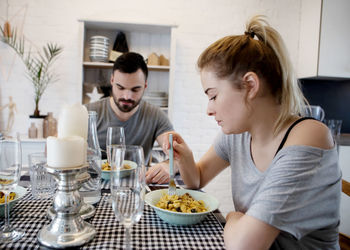 Close-up of young woman eating with man at home