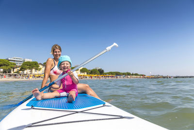 View  of happy woman and girl on paddleboard