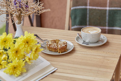 Aesthetic autumn lunch - coffee time for yourself book and dessert. cutting doughnut with cappuccino