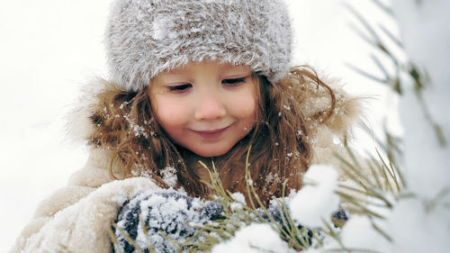 Christmas tree outdoor decoration. cutie, pretty little girl decorates snow-covered christmas tree 