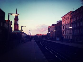 Road leading towards buildings at sunset