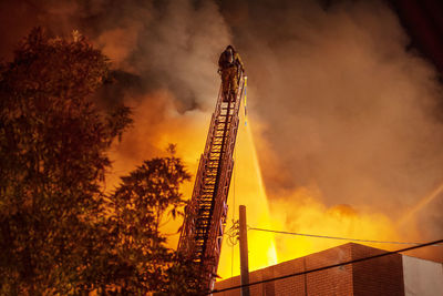 Rear view of firefighter spraying water on burning building