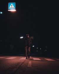 Full length of man walking on illuminated street at night