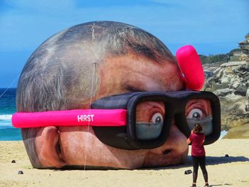 Full length of man taking selfie at beach against sky