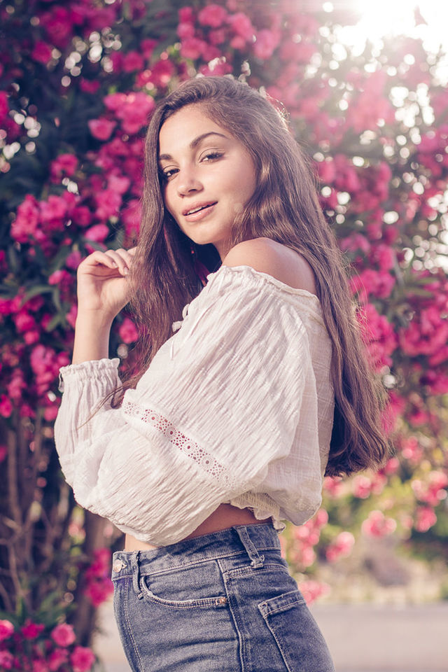 YOUNG WOMAN STANDING BY PINK FLOWER