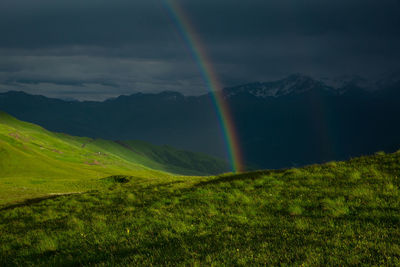Beautiful rainbow after rain in the mountains. scenic view of rainbow over mountains against sky