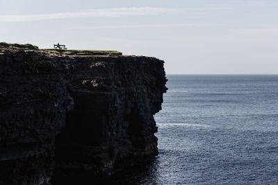 Scenic view of sea by cliff against sky