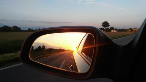 Close-up of side-view mirror at sunset