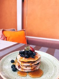 Syrup being poured on pancakes in plate